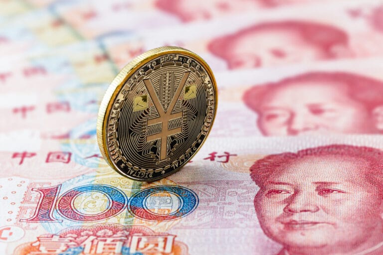 A golden yuan coin standing on Chinese 100 yuan banknotes, symbolizing China’s economic strategies and currency policies.