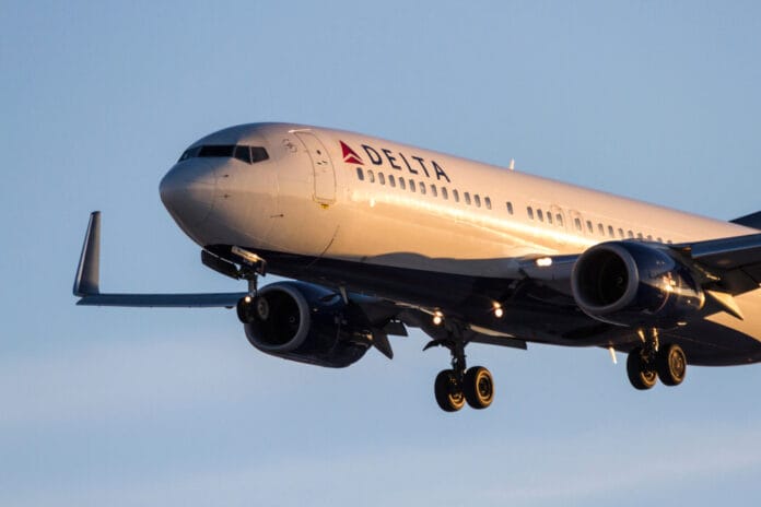 A Delta Air Lines Boeing 737 aircraft approaching for landing, captured in golden sunlight against a clear blue sky.