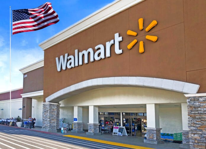 Walmart storefront with an American flag flying nearby on a sunny day.