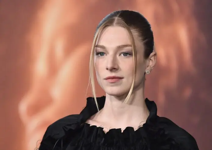 Person with blonde hair in a sleek hairstyle wearing a black outfit at a formal event.