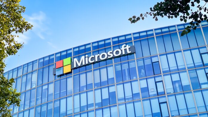 Microsoft office building with a glass facade reflecting the blue sky, featuring the Microsoft logo prominently displayed on the exterior.