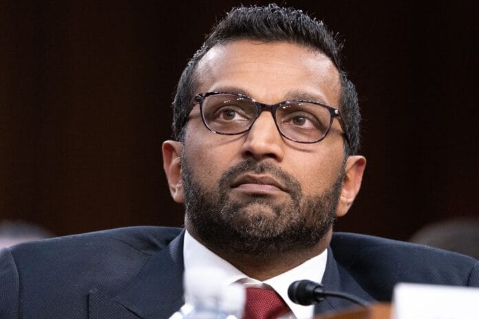 A close-up of a man wearing glasses and a suit, attentively listening during a formal hearing.